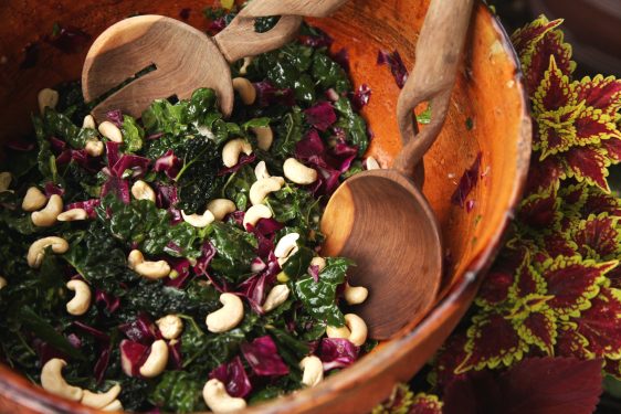 Cool Crisp Kale Cashew Mint Salad in a wooden bowl in front of plants