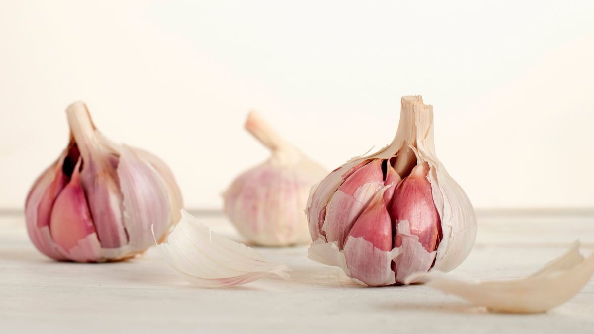 three garlic heads on a white table