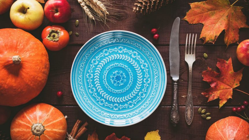 a blue plate with autumn leaves and vegetables around it