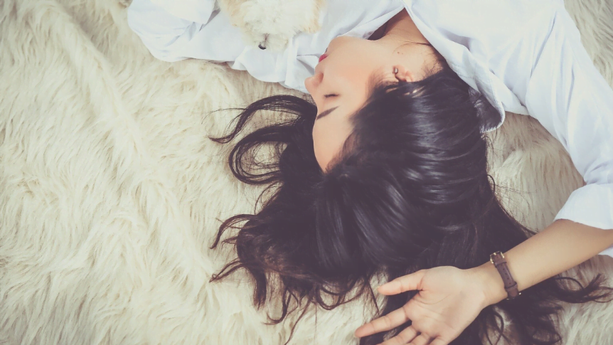 A lady with dark hair sleeping on a white fuzzy blanket