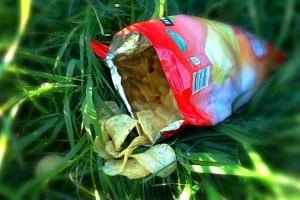 An open bag of processed food potato chips on grass