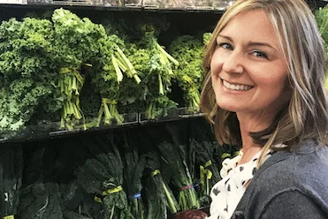 Graduate of Nutrition Therapy Institute standing in front of fresh produce.