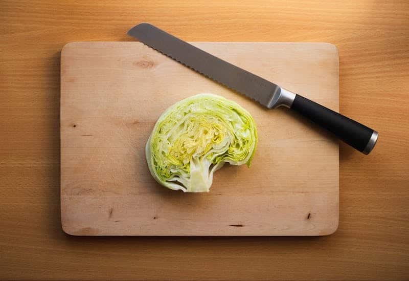 Cut cabbage resembling a brain on a wooden cutting board with a knife, symbolizing its brain-boosting benefits. Cabbage is rich in antioxidants and vitamin K, supporting cognitive health and reducing inflammation. Learn more at Nutrition Therapy Institute.