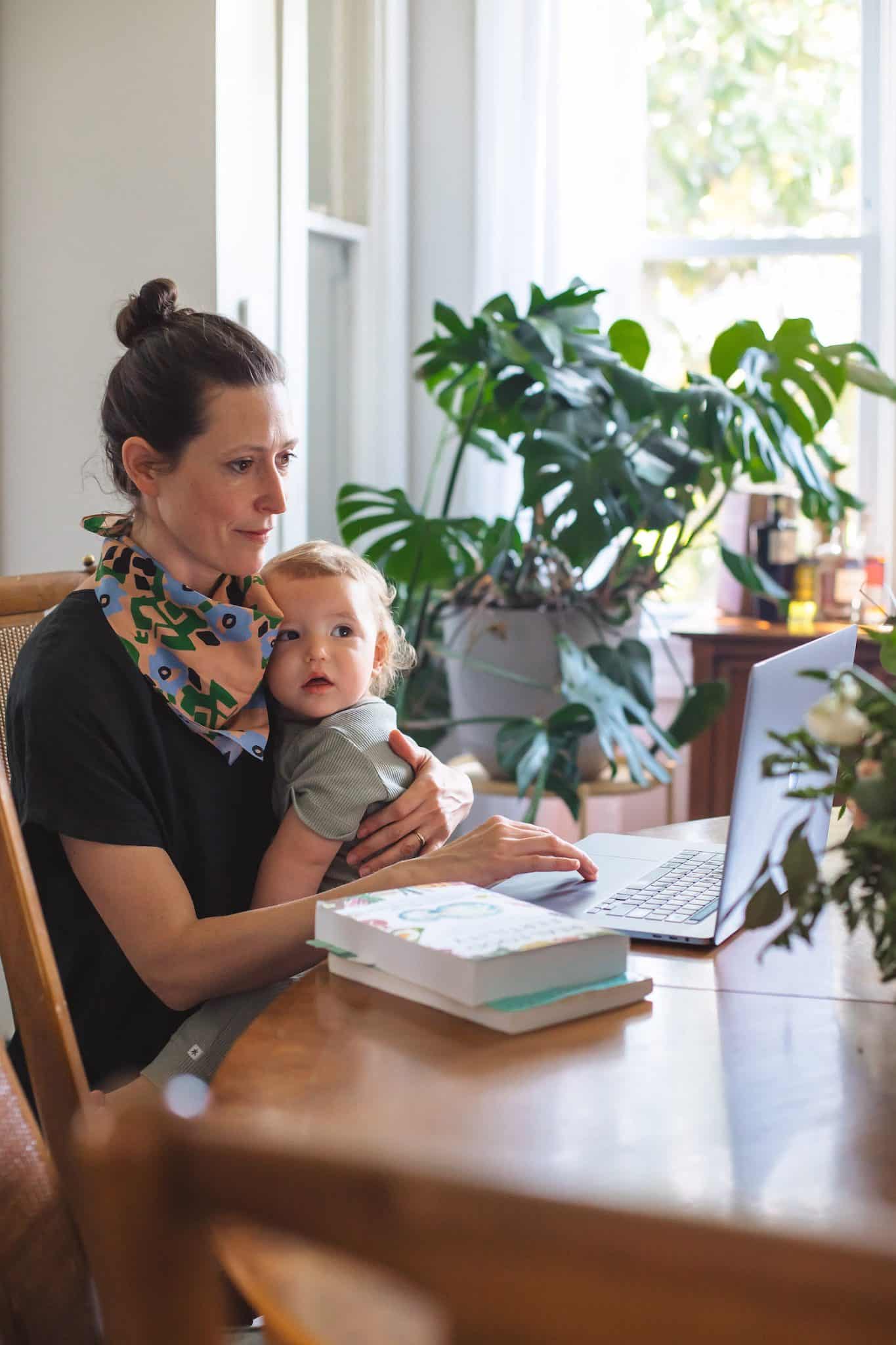 Nutrition Therapy Institute student balancing parenthood and education, studying the online Nutrition Therapist Master Certification program with their baby in their lap.