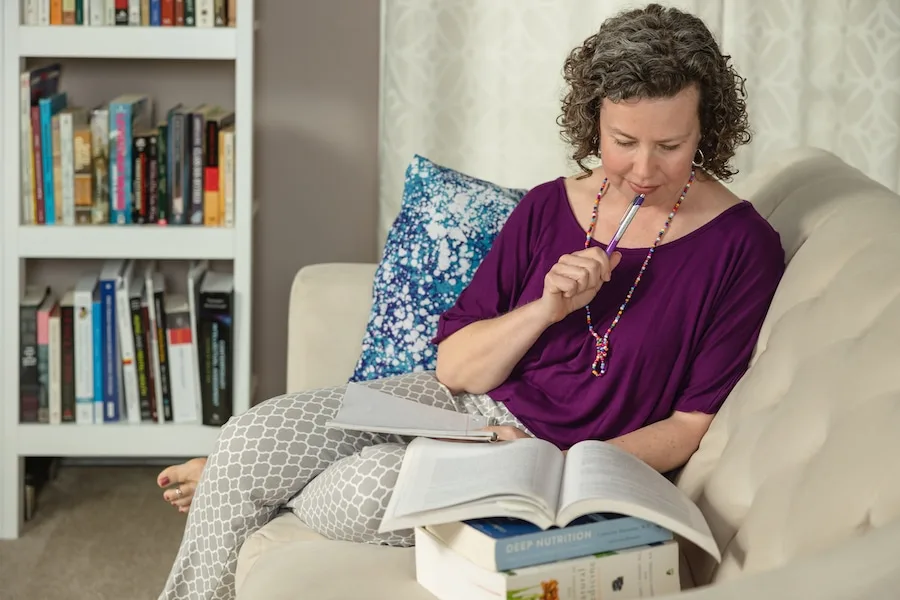 Nutrition Therapy Institute student studying nutrition books from the comfort of home, gaining expertise through the online Nutrition Therapist Master Certification program.