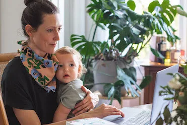 Busy NTI student balancing holistic nutrition studies and motherhood with her baby in her lap.