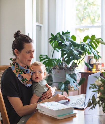 Busy NTI student balancing holistic nutrition studies and motherhood with her baby in her lap.