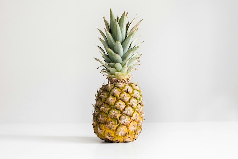 Whole pineapple on a white background, a natural source of bromelain that may help reduce seasonal allergy symptoms.
