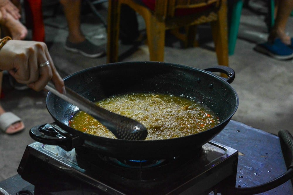 Pan filled with cooking oil heating on the stove, representing the use of processed fats like partially hydrogenated oils and trans fat alternatives.