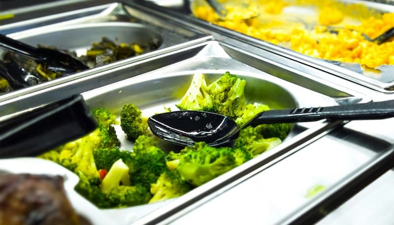 Steamed broccoli in a cafeteria tray as part of nutrient-dense meal planning for facilities.
